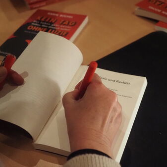 Eine Person schreibt eine Widmung in ein Buch
