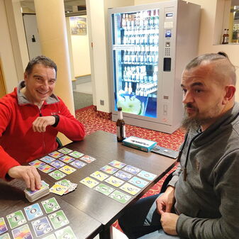 Zwei Personen sitzen an einem Tisch mit Kartenspielen