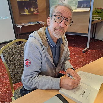 Eine Person signiert ein Buch